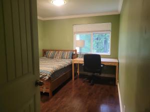 a bedroom with a bed and a desk and a window at Vancouver Jenny's Guesthouse in Coquitlam
