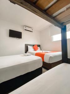 Habitación con 2 camas y TV en la pared. en Hotel G Cartagena, en Cartagena de Indias