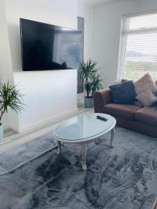a living room with a coffee table and a tv at Spectacular 4 Bedroom Sea View Residential Home in Bangor