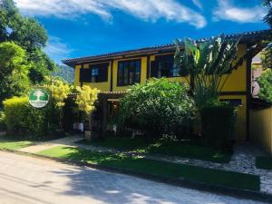 een geel huis op een straat met planten bij Pousada Aroeira in Barra do Sahy