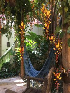 a hammock in a garden with flowers at Pousada Aroeira in Barra do Sahy
