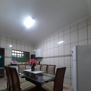 comedor con mesa, sillas y nevera en Recanto Rafaella, en Olímpia
