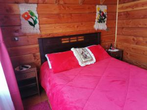 a bedroom with a red bed with wooden walls at Cabañas El Diuco en Coñaripe 4 in Coñaripe