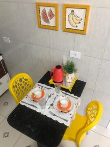 a table with yellow chairs and a tea pot on it at Manancial Flats in Maragogi