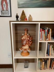 a book shelf with a statue on top of it at Apartamento confortável, região do Iguatemi in Salvador