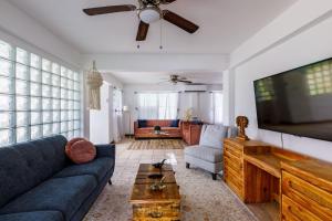 a living room with a blue couch and a flat screen tv at Rainforest Retreat 15 min from the beach in Luquillo