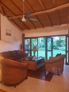 a living room with wicker furniture and a ceiling fan at Paradise Cove Resort in Port Vila