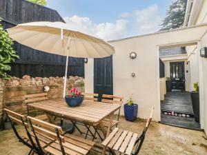 uma mesa de madeira com um guarda-chuva num pátio em Monterey Mews em Torquay