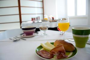 a plate with meat and cheese and a glass of orange juice at Hotel Abade João in Montemor-o-Velho