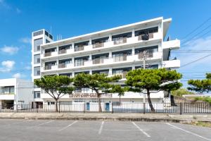 un edificio bianco con alberi di fronte di Type D Room 35平米 -ウル エスポワール石垣- a Isola di Ishigaki