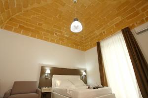 a bedroom with a bed and a chair and a window at Casa Vacanze Woodhouse in Marsala