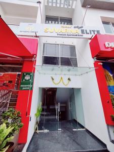 una tienda frente a un edificio blanco con una puerta giratoria en Suvarna Elite - Premium Apartment Hotel, en Mysore
