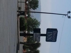 a couple of signs hanging from a street pole at Desert Inn in Van Horn