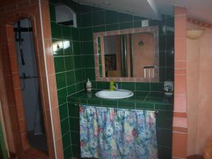 a green tiled bathroom with a sink and a mirror at coquet f2 avec petite terrasse in Canet-en-Roussillon