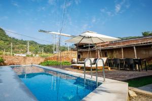 - une piscine avec un parasol et des chaises à côté d'une maison dans l'établissement CMYK Stoneyards by the Great Wall, à Huairou