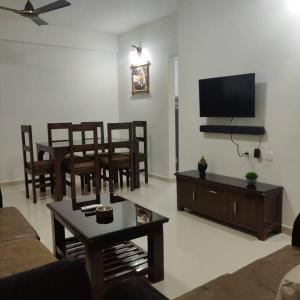 a living room with a couch and a table and a tv at Kivi's kozy 2bhk luxurious apartment Goa by leela homes in Arpora