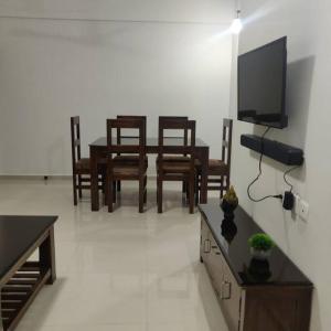 sala de estar con mesa, sillas y TV en Kivi's kozy 2bhk luxurious apartment Goa by leela homes, en Arpora