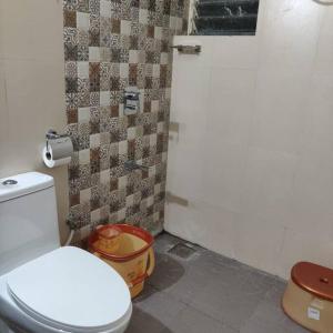 baño con aseo blanco y pared de azulejos en Kivi's kozy 2bhk luxurious apartment Goa by leela homes, en Arpora