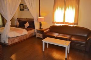 a bedroom with a couch and a bed and a table at Joglo Villa Bali in Denpasar