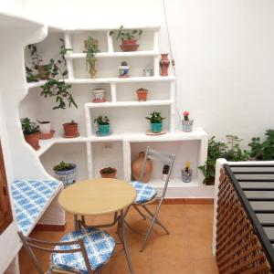 um quarto com uma mesa e cadeiras e prateleiras com vasos de plantas em Lovely Town House Casa La Senda em Grazalema