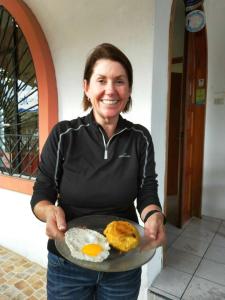 una donna che tiene in mano un piatto di uova e biscotti di Casa de Nelly a Puerto Baquerizo Moreno
