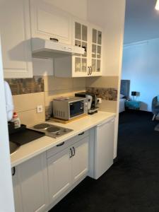 eine Küche mit weißen Schränken und einer Mikrowelle auf der Theke in der Unterkunft WooW Apartments in Velika Gorica