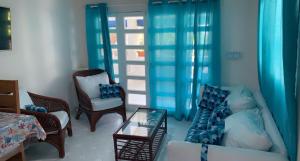 a living room with blue curtains and a couch and chairs at La Gaviota B3 in Juan Dolio