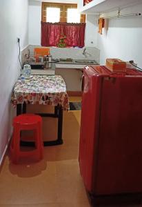 a small kitchen with a table and a red refrigerator at Kuttickattil Gardens Homestay in Kottayam