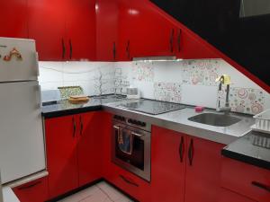 a kitchen with red cabinets and a white refrigerator at Djakuzi Viktorija in Belgrade