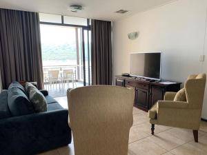 a living room with a couch and a tv and chairs at 307 Point Bay in Durban