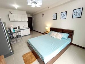 a bedroom with a large bed and a kitchen at Lovely Studio Type Condo - fully furnished in Mactan