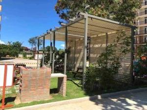 a wooden pergola with a bench in the grass at Lovely Studio Type Condo - fully furnished in Mactan