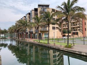a building next to a canal with palm trees at 307 Point Bay in Durban