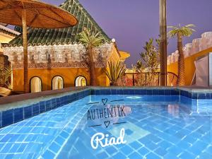 a swimming pool in front of a building with an umbrella at Riad Kech Soul Boutique & Spa in Marrakesh