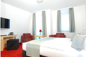 a hotel room with a bed and two red chairs at Pension Heimchen in Bansin