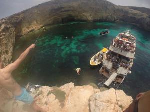a man standing on a cliff looking at a boat in a cave at Marco Polo Party Hostel in St. Julianʼs