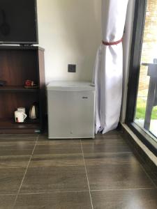 einen kleinen weißen Kühlschrank in einem Zimmer mit Fenster in der Unterkunft Mount shadows in Ella