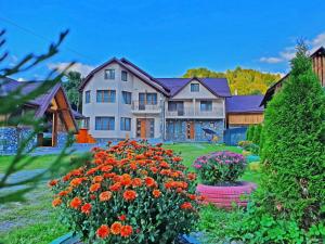 ein großes Haus mit Blumen im Hof in der Unterkunft Pensiunea Dorul de Munte nr 222 in Rucăr