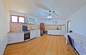 a large kitchen with white cabinets and a wooden floor at Pensiunea Dorul de Munte nr 222 in Rucăr