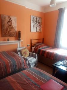 two beds in a room with orange walls at Lea Hurst B & B in Bournemouth
