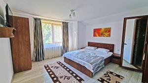 a bedroom with a bed and a large window at Pensiunea Dorul de Munte nr 222 in Rucăr +29 photos