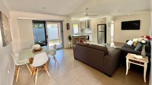 a living room with a couch and a table at Home away from home - Modern luxury in central Bundaberg in Bundaberg