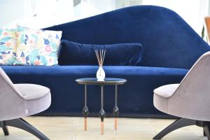 a blue couch with two chairs and a table with a vase on it at Giuggiulena in Siracusa