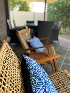 a patio with a chair and pillows and a table at Home away from home - Modern luxury in central Bundaberg in Bundaberg