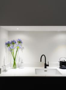 Una encimera de cocina con un fregadero y flores moradas en un jarrón. en Deluxe Apartment in Historic Quarter near Beaches, en Aberystwyth 6 fotos más