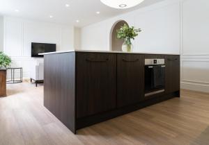 Una cocina con un mueble de madera y un televisor en una habitación. en Deluxe Apartment in Historic Quarter near Beaches, en Aberystwyth