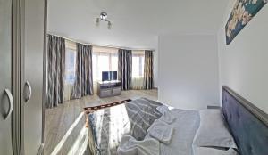 a bedroom with a bed and a tv and windows at Pensiunea Dorul de Munte nr 222 in Rucăr