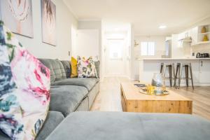 a living room with a gray couch and a wooden coffee table at Plettenberg Bay Unit 2 Greenpoint Mews Apartment with Backup Power in Plettenberg Bay