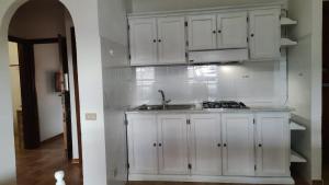 a kitchen with white cabinets and a sink at Residence Spiaggia Bianca in Golfo Aranci