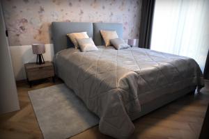 ein Schlafzimmer mit einem großen Bett mit einer grauen Decke in der Unterkunft Apartmán Golfballs in Šajdíkove Humence